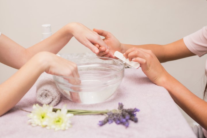 Nail technician giving customer a manicure at the beauty salon