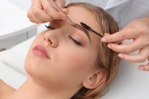 Young woman having eyebrow correction procedure in beauty salon