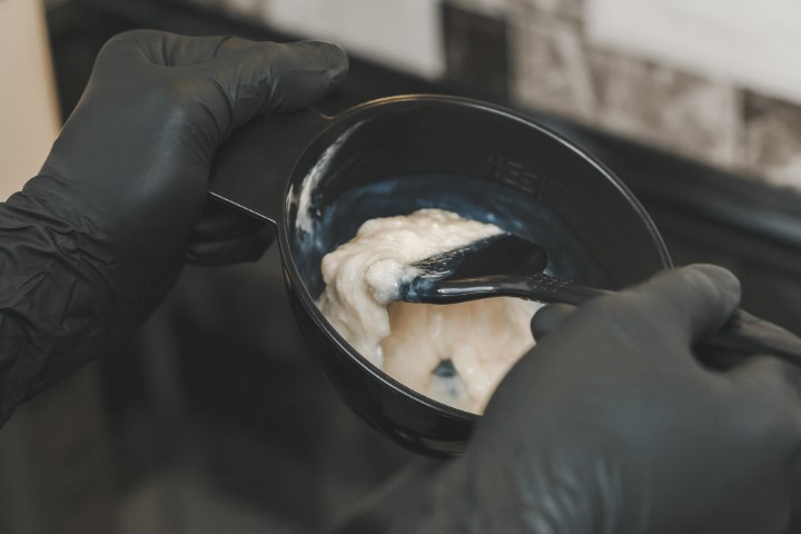Stylist preparing a hair dye in a container, hairdresser salon concept