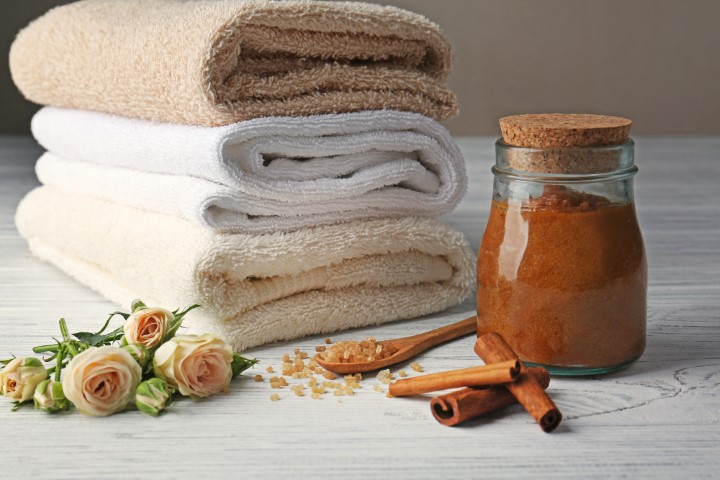 Body scrub and cinnamon on wooden table