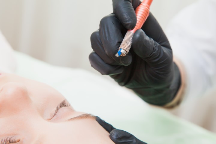 Female cosmetologist with manual tattoo pen machine