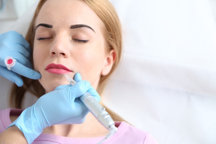 Cosmetologist applying permanent make up on lips
