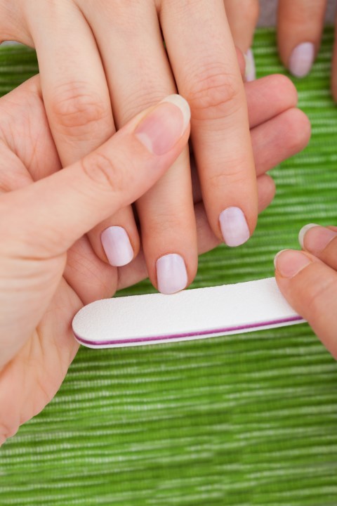 Beautician Filing Nails Of Woman